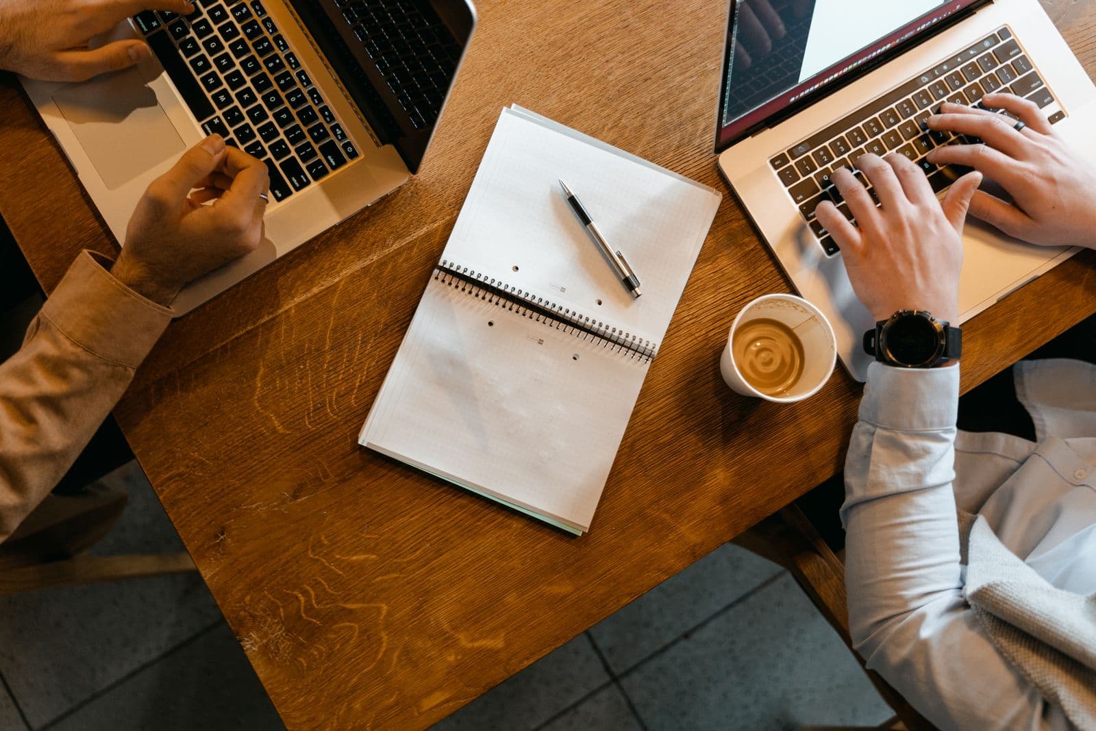 Overhead shot of hands on a laptop with notebooks and coffee, representative of the operator workflow Anystay supports.